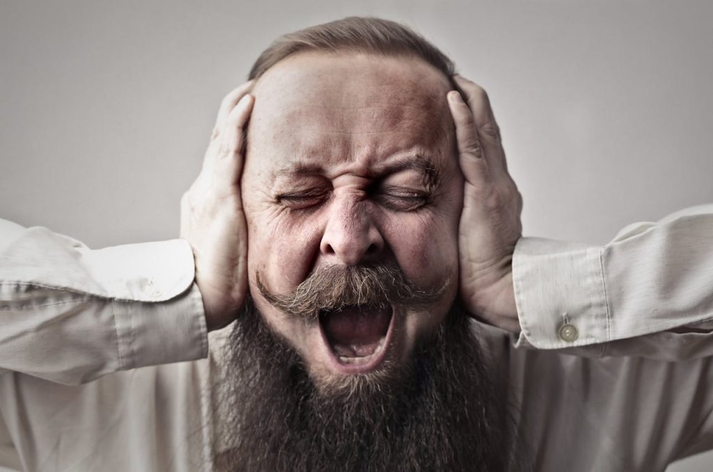A very frustrated man needing ear wax removal by microsuction